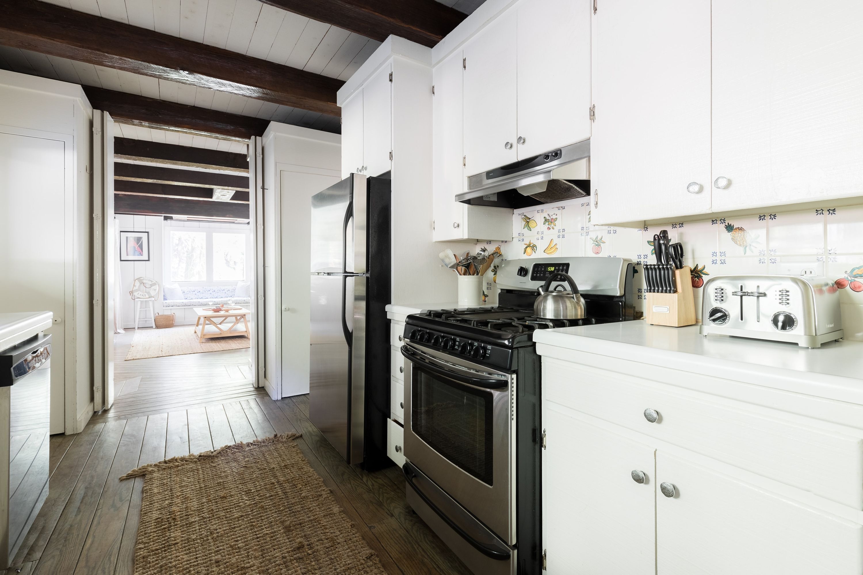 A kitchen with white cabinets, a stainless steel refrigerator, an oven, and a toaster.