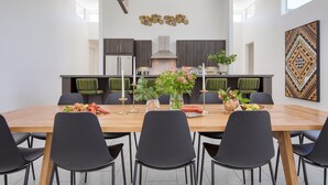 A modern kitchen with dark cabinets, a central island, and a dining area with a wooden table and black chairs.