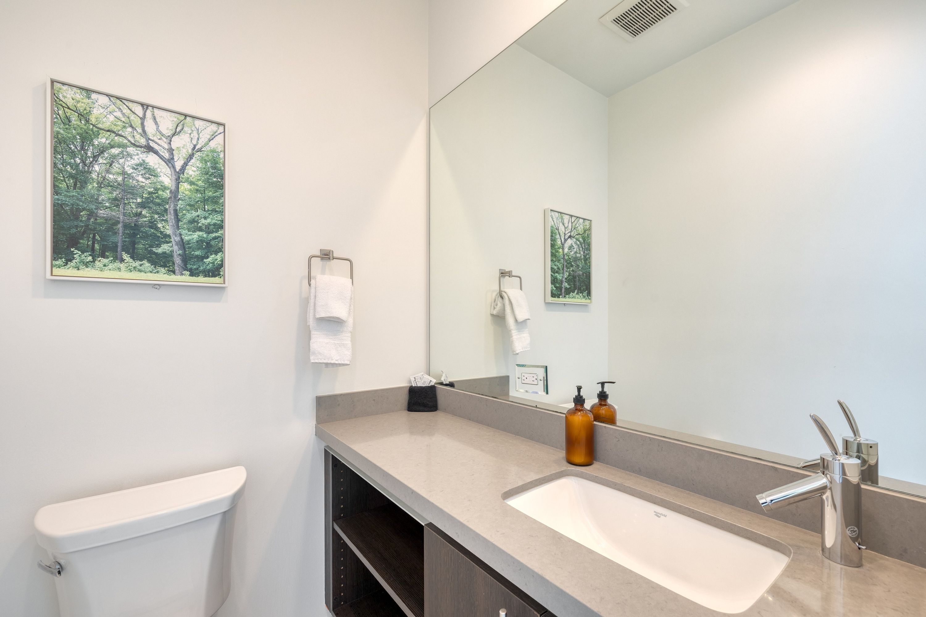 Une salle de bain moderne avec des toilettes, un lavabo et un grand miroir.