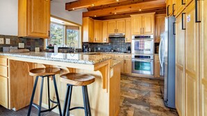 A spacious kitchen with wooden cabinets, a granite countertop, and stainless steel appliances. - Endless View Lodge by Avantstay Incredible Views Close To Bear Mountain Ski Resort w Hot Tub (Big Bear Lake)