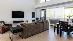 A modern living room with a large sectional sofa, a flat-screen TV, a dining table with chairs, and a ceiling fan. - Ivory II By Avantstay Gorgeous Spacious Home w Views Close To Old Town (Scottsdale)