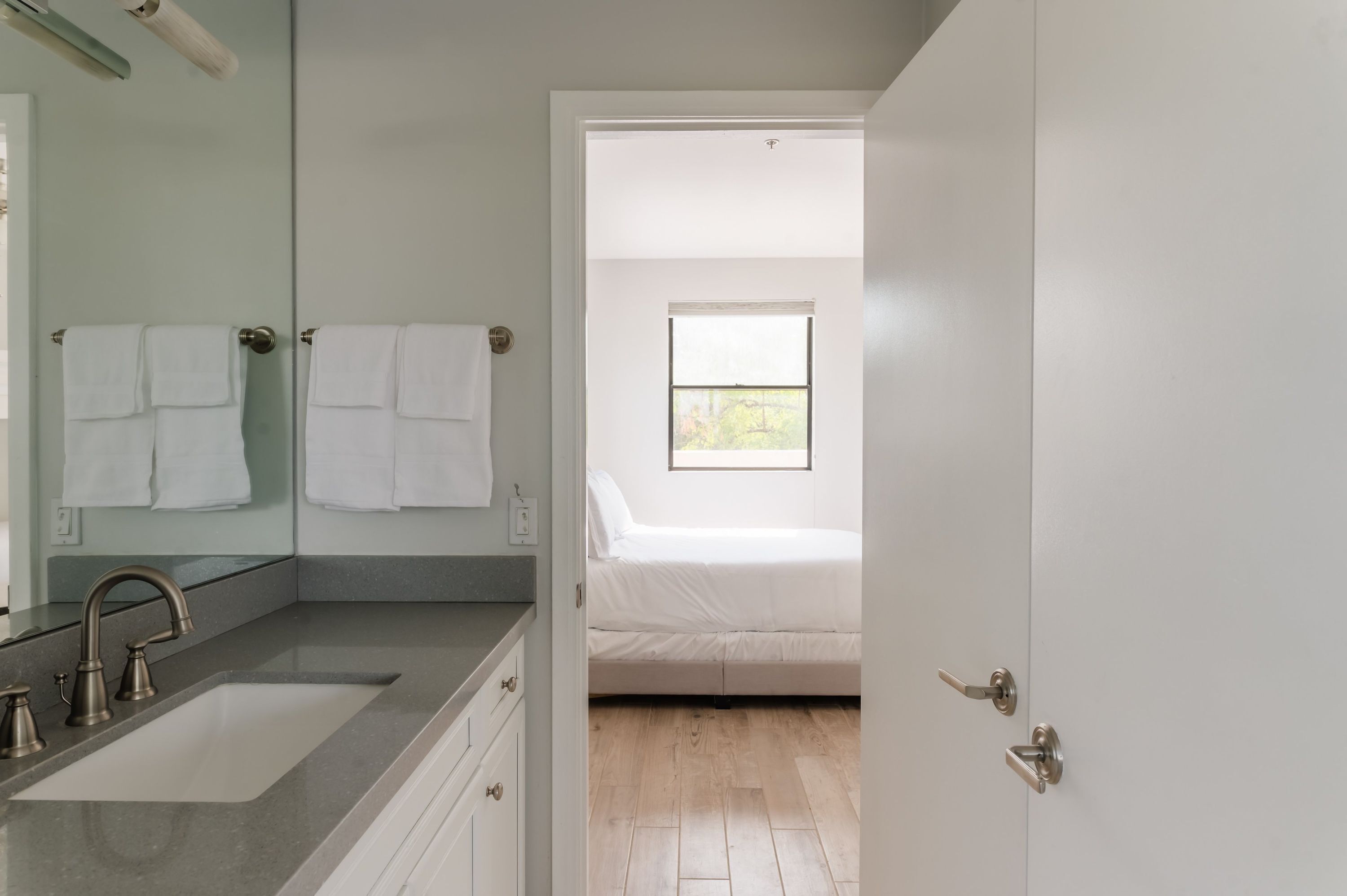 A modern bathroom with a large mirror, a sink, and two towels hanging on the wall.