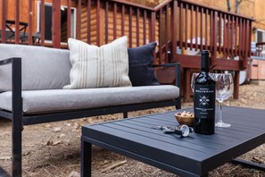 A black table with a bottle of Chateau Souverain wine, a glass, and a bowl of snacks. - Jumper By Avantstay Serene Stylish Cabin w Hot Tub (Big Bear Lake)