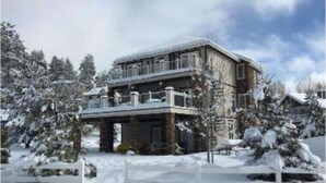 A two-story building with a balcony, surrounded by snow-covered trees. - Boulder Bay Lodge by Avantstay Boulder Bay Home w Hot Tub Large Patio Game Room (Big Bear Lake)