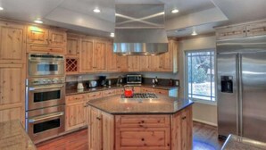 A modern kitchen with wooden cabinets, stainless steel appliances, and a central island. - Boulder Bay Lodge by Avantstay Boulder Bay Home w Hot Tub Large Patio Game Room (Big Bear Lake)