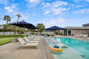 A pool area with lounge chairs, umbrellas, and a poolside table. - Polo Villa 10 by Avantstay Backyard Oasis w Putting Green 260320 6 Bedrooms (La Quinta)