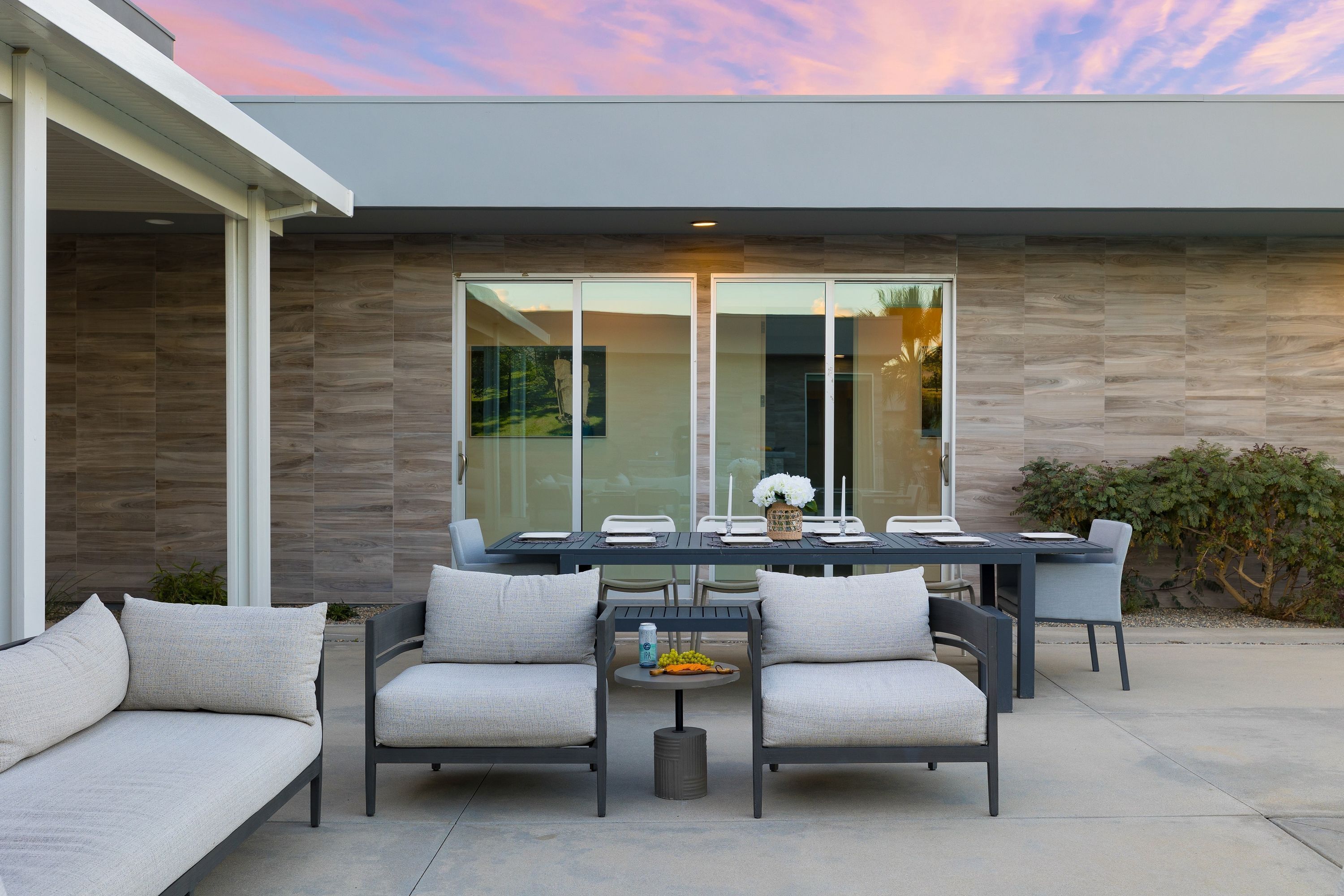 An outdoor patio with a dining table, chairs, and a sofa.