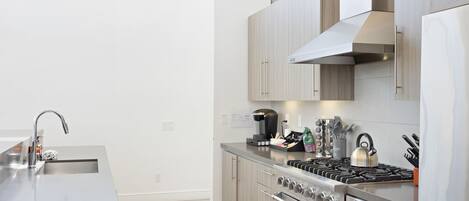 Una cocina moderna con electrodomésticos de acero inoxidable, armarios de madera y una isla grande con un fregadero.