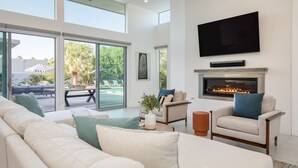 Un salón amplio con un sofá grande, una chimenea y un televisor montado en la pared.