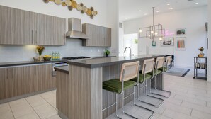 Una cocina moderna con una isla central, taburetes de bar y un adorno decorativo en la pared.