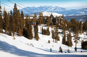 Ein Skigebiet mit Berghotel, Skiliften und einem verschneiten Berg im Hintergrund.
