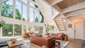A spacious living room with a large sofa, a coffee table, and a staircase leading to an upper level.