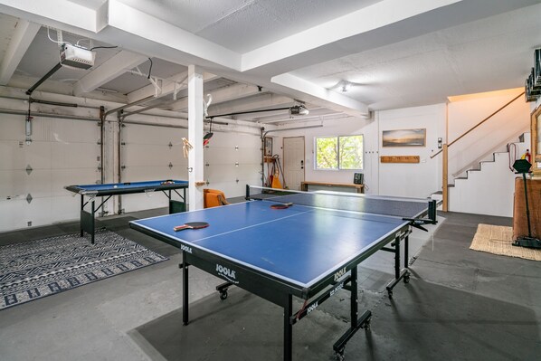 Amplio espacio interior con mesa de ping-pong, una mesa más pequeña y un aro de baloncesto.