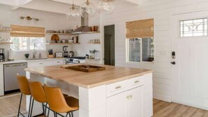 A modern kitchen with white cabinetry, a wooden island, and pendant lights.