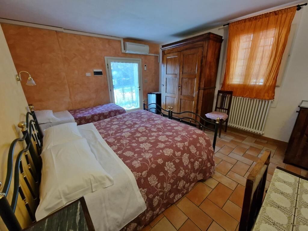 A bedroom with two beds, a wardrobe, a radiator, and a window with curtains.