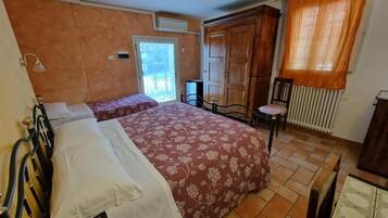 Un dormitorio con dos camas, un armario, un radiador y una ventana con cortinas.