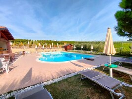Una piscina al aire libre de temporada, sombrillas