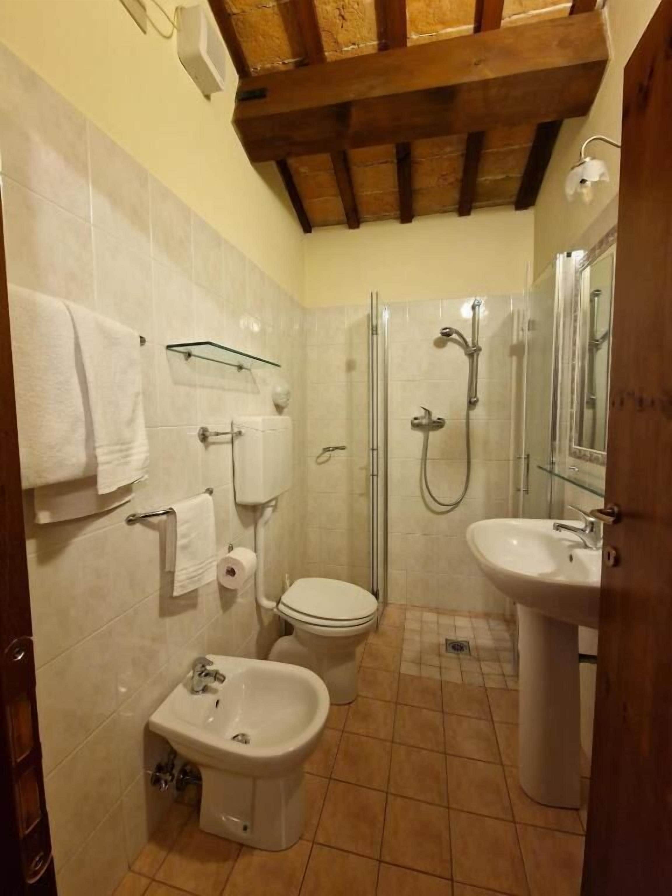 Ein kleines Badezimmer mit Toilette, Bidet, Waschbecken und Dusche.