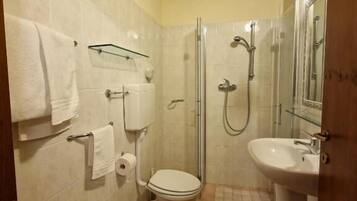 Ein kleines Badezimmer mit Toilette, Bidet, Waschbecken und Dusche.
