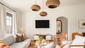 Un salon moderne avec un canapé, des fauteuils, une table basse et un téléviseur fixé au mur.