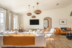 A modern living room with a sofa, armchairs, a coffee table, and a TV mounted on the wall.