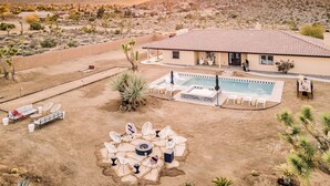 Un paysage désertique avec une piscine, un espace de détente extérieur et un bâtiment doté d’un toit en tuiles.