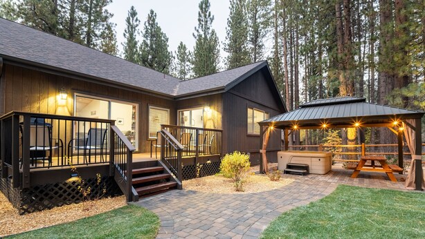 A lodge with a covered patio, outdoor seating, and a staircase leading to the entrance. - Lazy Bear Lodge by Avantstay Pine Tree Paradise w Game Room (Big Bear Lake)