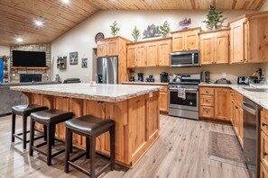 A spacious kitchen with wooden cabinets, a large island with bar stools, a built-in oven, and a microwave.