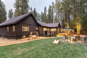 A rustic cabin with a deck, a fire pit, and a swing set.