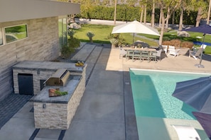 A modern outdoor patio with a barbecue area, a pool, and outdoor seating. - Polo Villa 6 by Avantstay Features Expansive Putting Green Pool Spa Outdoor Firepit 260324 5 Bedrooms (La Quinta)