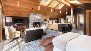 A spacious living area with a fireplace, stone flooring, and wooden ceiling beams.