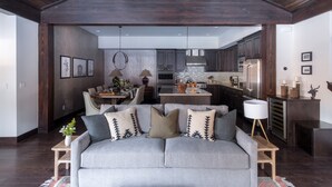 A modern living room with a grey sofa, wooden coffee table, and a dining area with a chandelier. - Maple by Avantstay Modern Mountain Home w Cozy Fire Pit 15 Mins frm Northstar (Truckee)