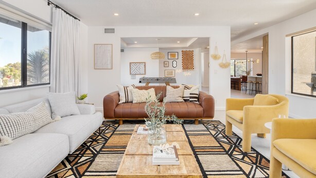 A modern living room with a sofa, coffee table, and yellow armchairs. There is a dining area in the background. - Lava Rocks by Avantstay Gorgeous Desert Haven w Pool Hot Tub Fire Pit Ping Pong (Yucca Valley)