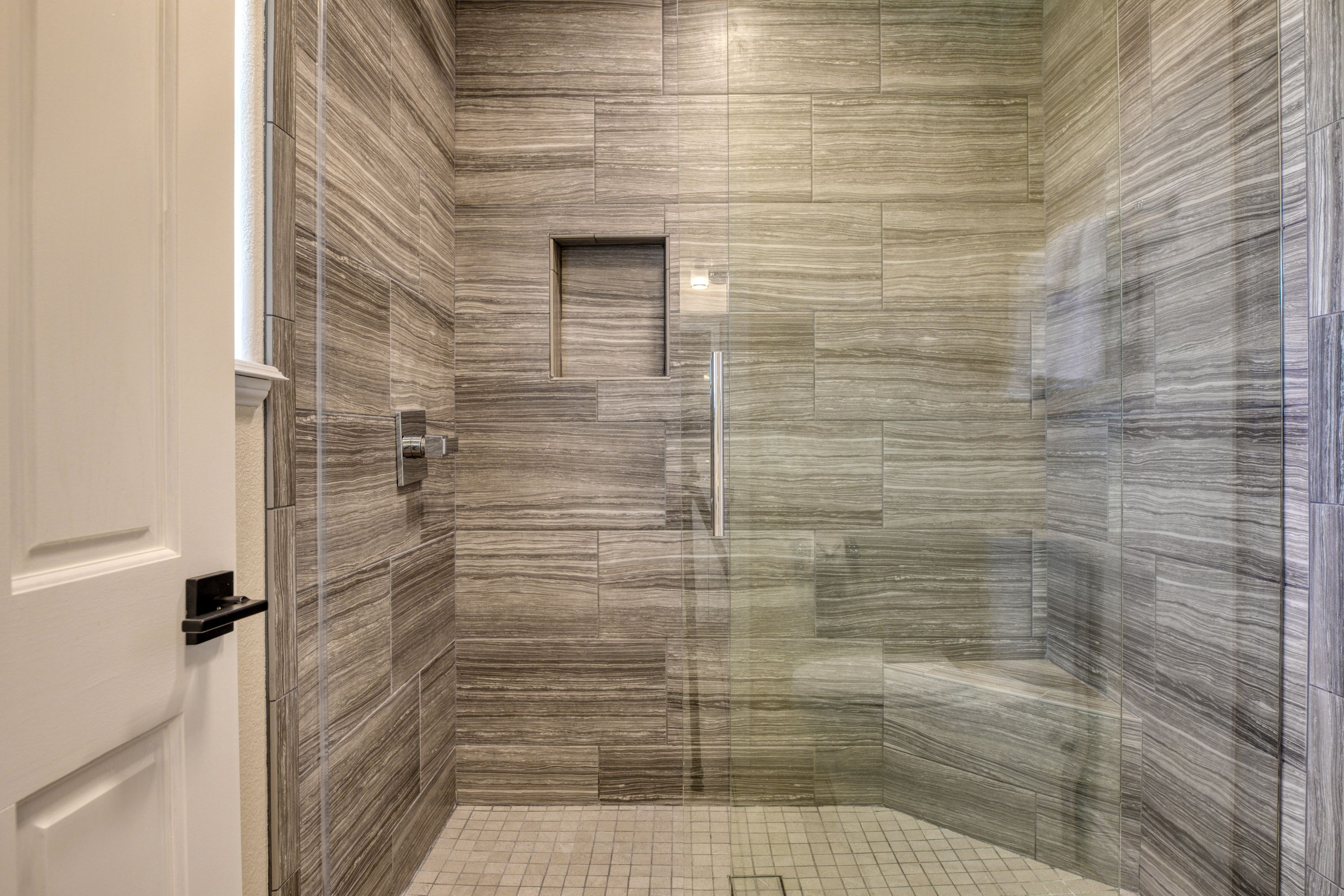 Eine moderne Dusche mit Glastür und Fliesenboden.
