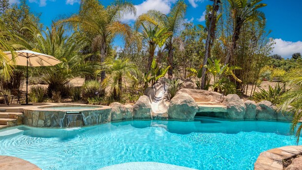 Une piscine à l’eau cristalline, entourée d’une végétation tropicale et de rochers.
