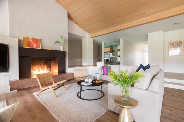 A modern living room with a fireplace, a sofa, a coffee table, and a TV.