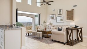 A spacious living area with a large window, a ceiling fan, and a coffee table. - Malbec by Avantstay Incredible Estate w Panoramic Views Bocce Ball Court (Temecula)