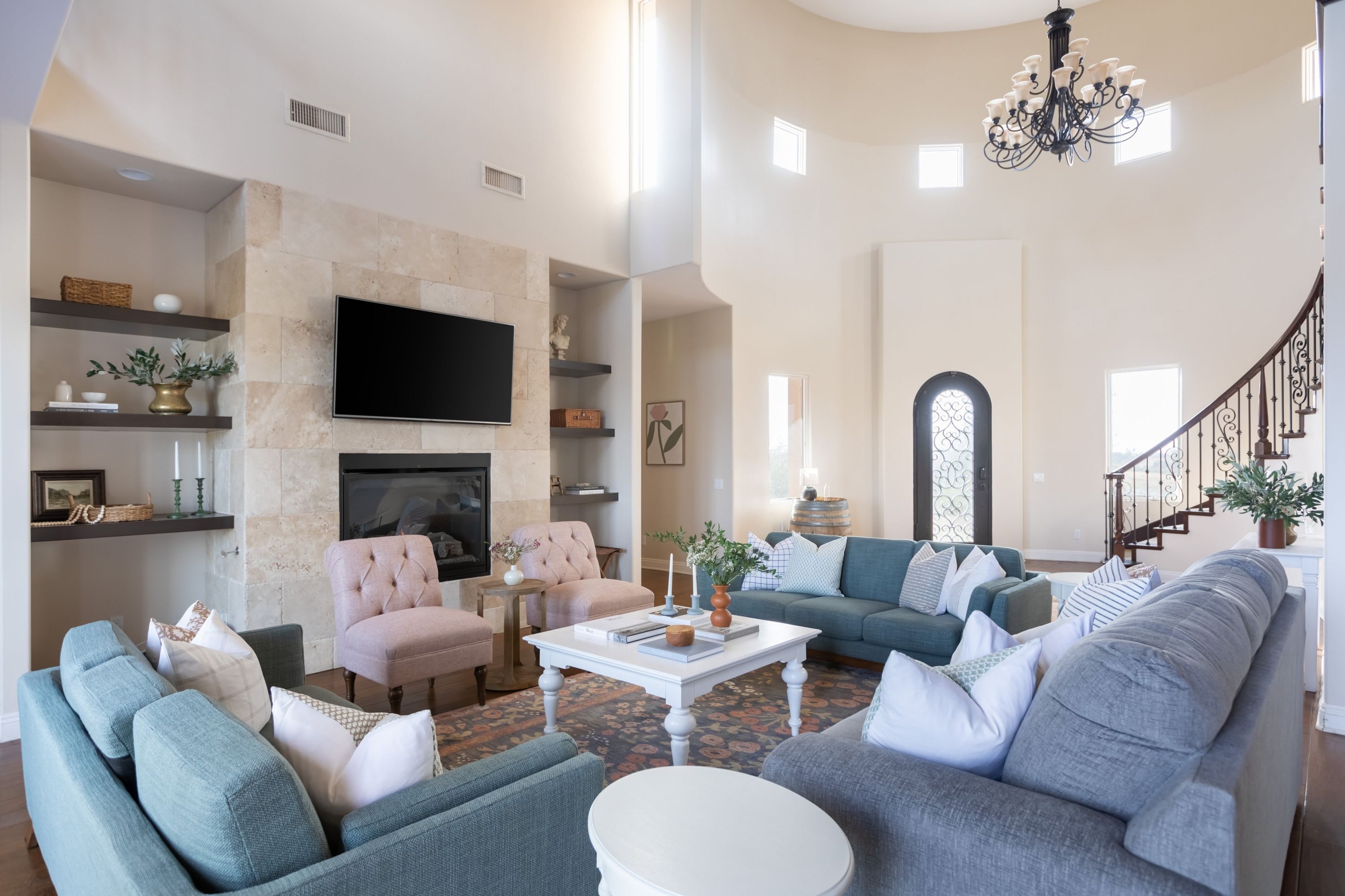 Un salón amplio con chimenea, televisor y una escalera que sube a otro nivel.