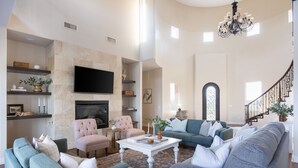 A spacious living room with a fireplace, a television, and a staircase leading to another level.