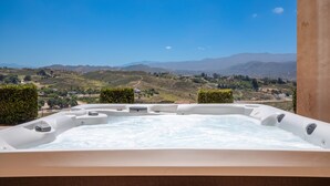 A hot tub with a scenic view of hills and a clear sky.