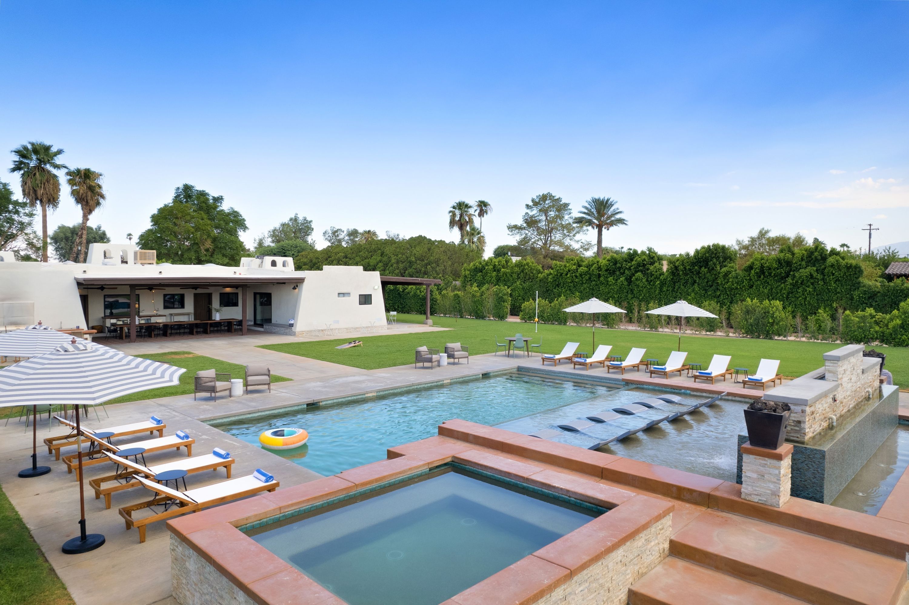 A pool area with lounge chairs, a hot tub, and a covered patio.