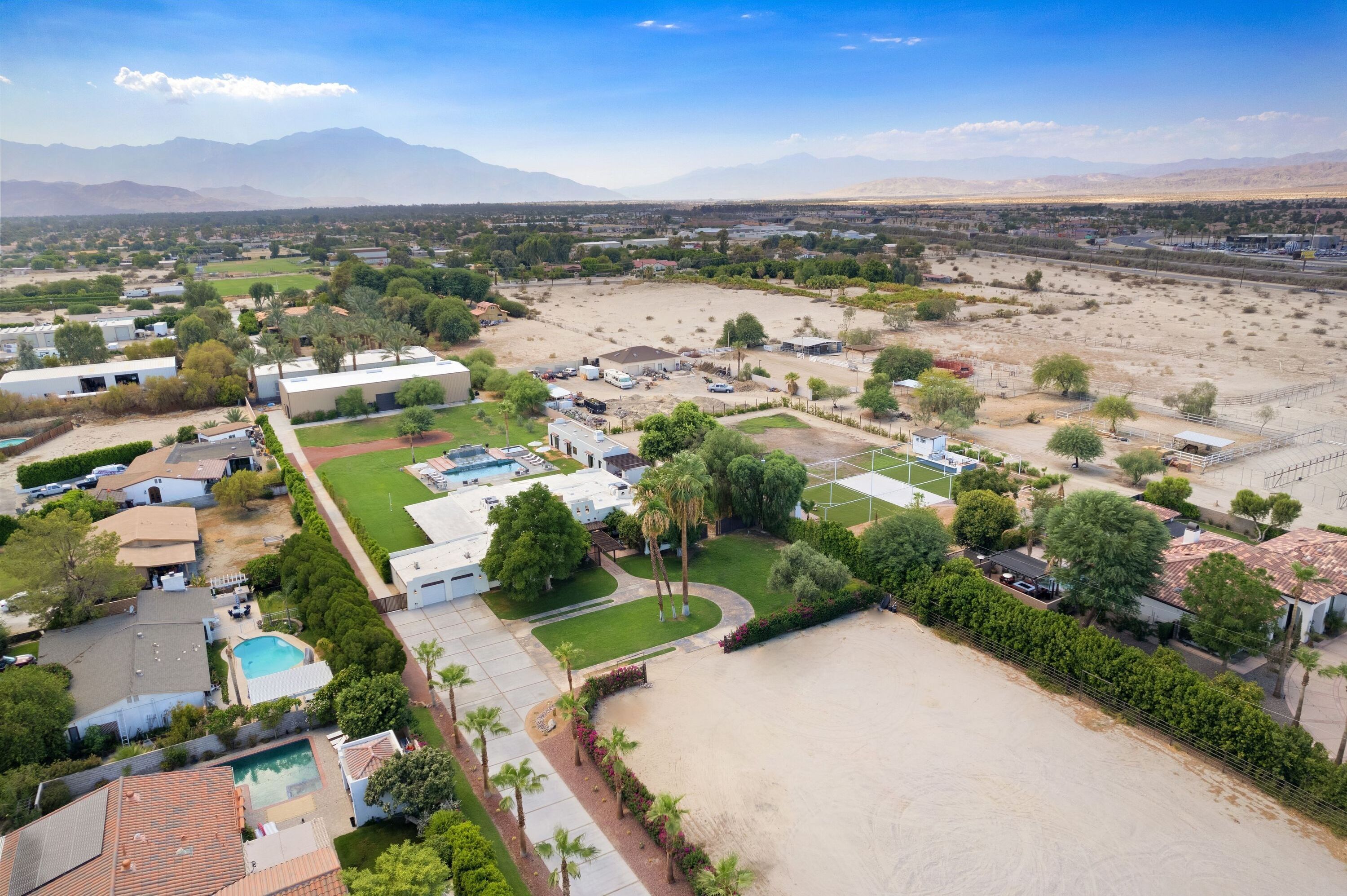 An aerial view of a residential area with houses, a large open field, and mountains in the background.