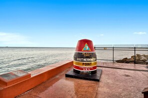 Un letrero desgastado, de color rojo y amarillo, con la inscripción 'South Hernmose Point, Estados Unidos continentales, Key West, Florida'.