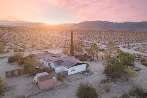 A desert landscape with a house featuring solar panels, a swimming pool, and a fenced yard. - Asteroid by Avantstay Unique Ranch Retreat Just Outside Joshua Tree Permit Vhr22-094 (Twentynine Palms)