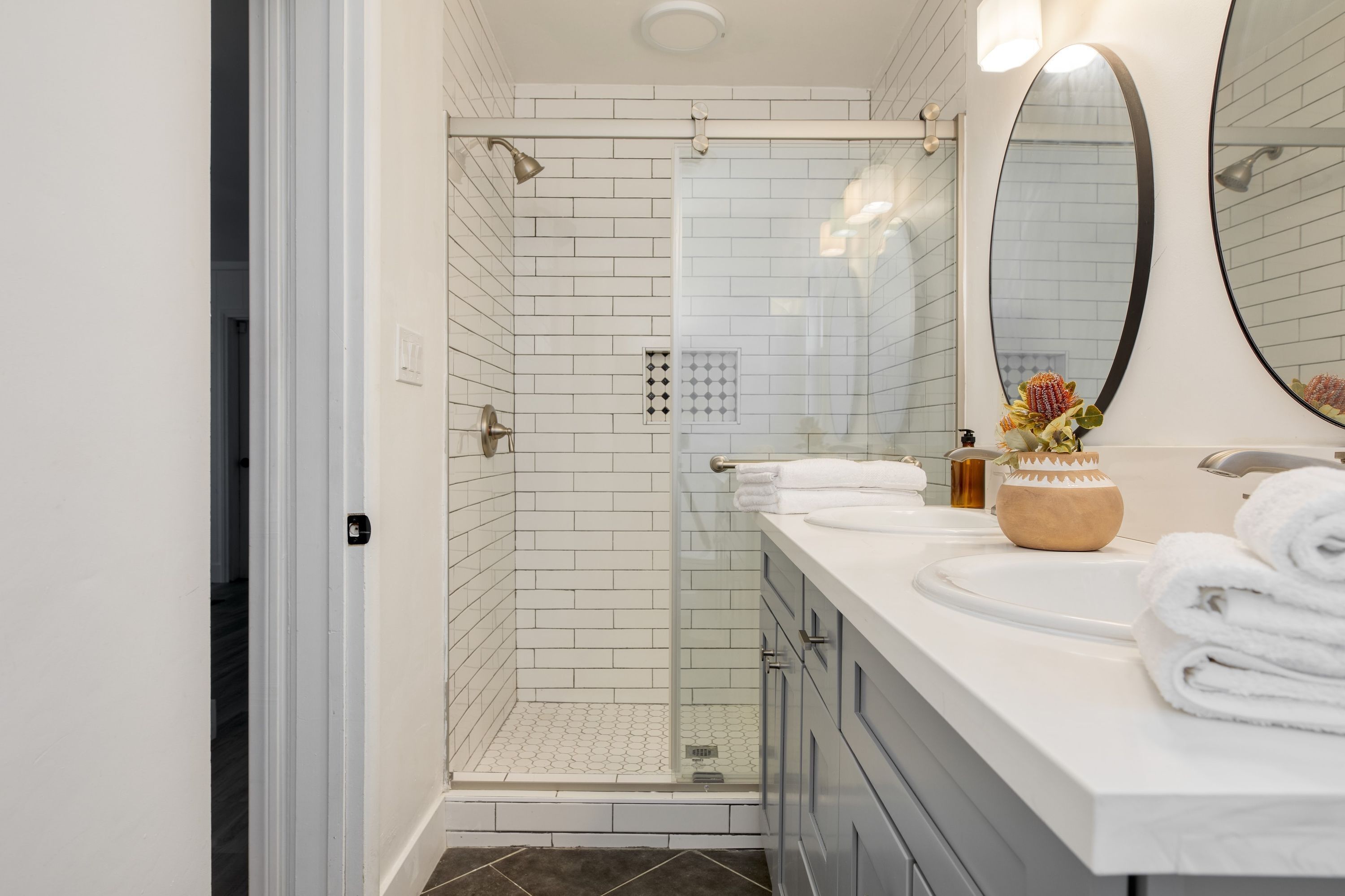 A modern bathroom with a walk-in shower, a large mirror, and a vanity with a sink and towel rack.