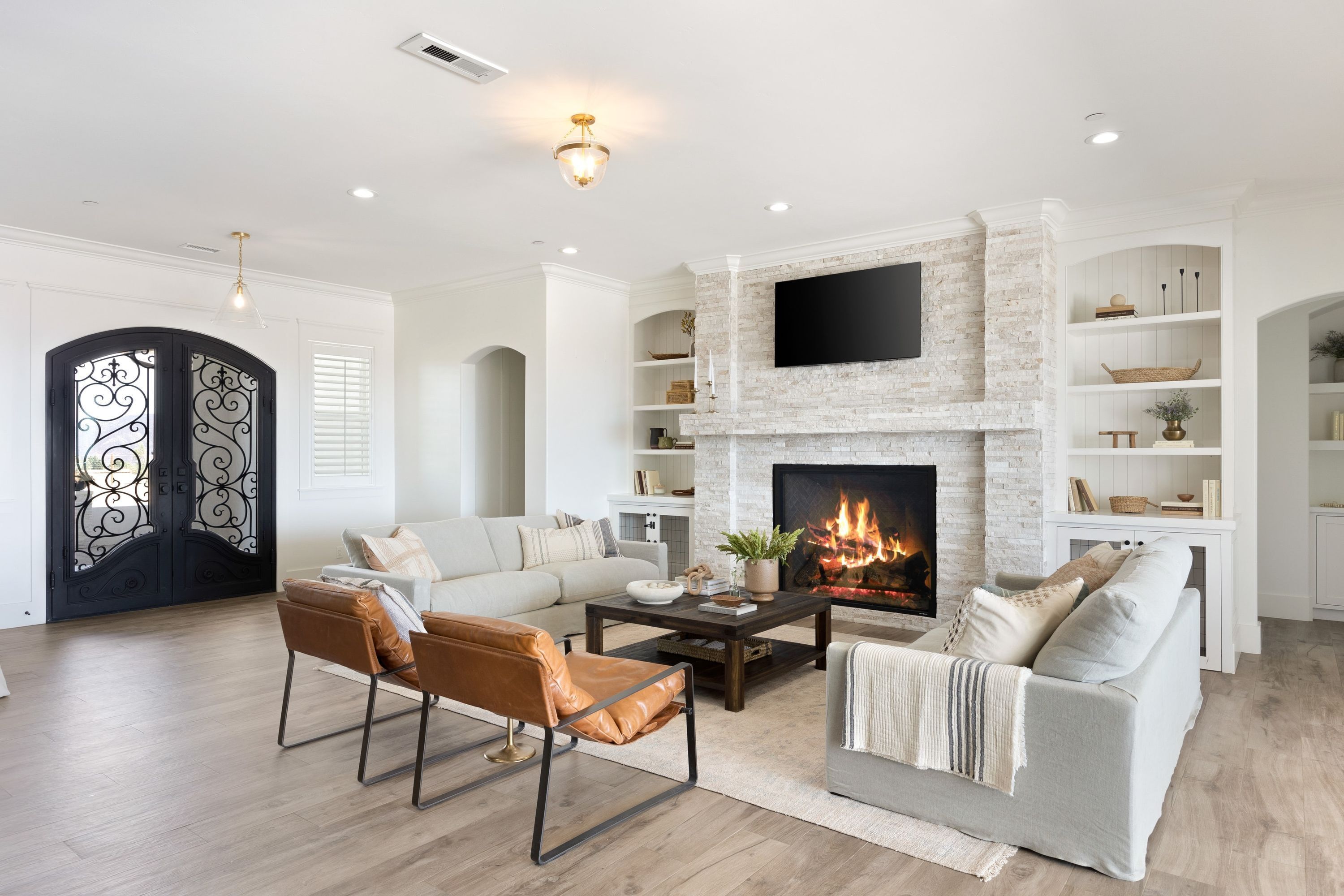 A living room with a fireplace, a sofa, a coffee table, and a TV mounted above the fireplace.