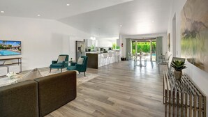 A spacious living area with a sofa, teal chairs, a TV, and a kitchen in the background. - Catalina by Avantstay Fully Remodeled Palm Springs Haven Pool Permit 3432 (Palm Springs)
