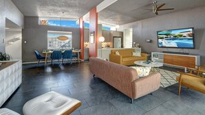 A modern living room with a sofa, coffee table, and TV. There is a dining area with chairs and a table. - Biskra by Avantstay Classic Palm Springs Getaway W Outdoor Living Pool Permit 4869 (Palm Springs)