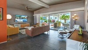 A spacious living area with a modern sofa, a flat-screen TV, and a dining area with a table and chairs. - Biskra by Avantstay Classic Palm Springs Getaway W Outdoor Living Pool Permit 4869 (Palm Springs)
