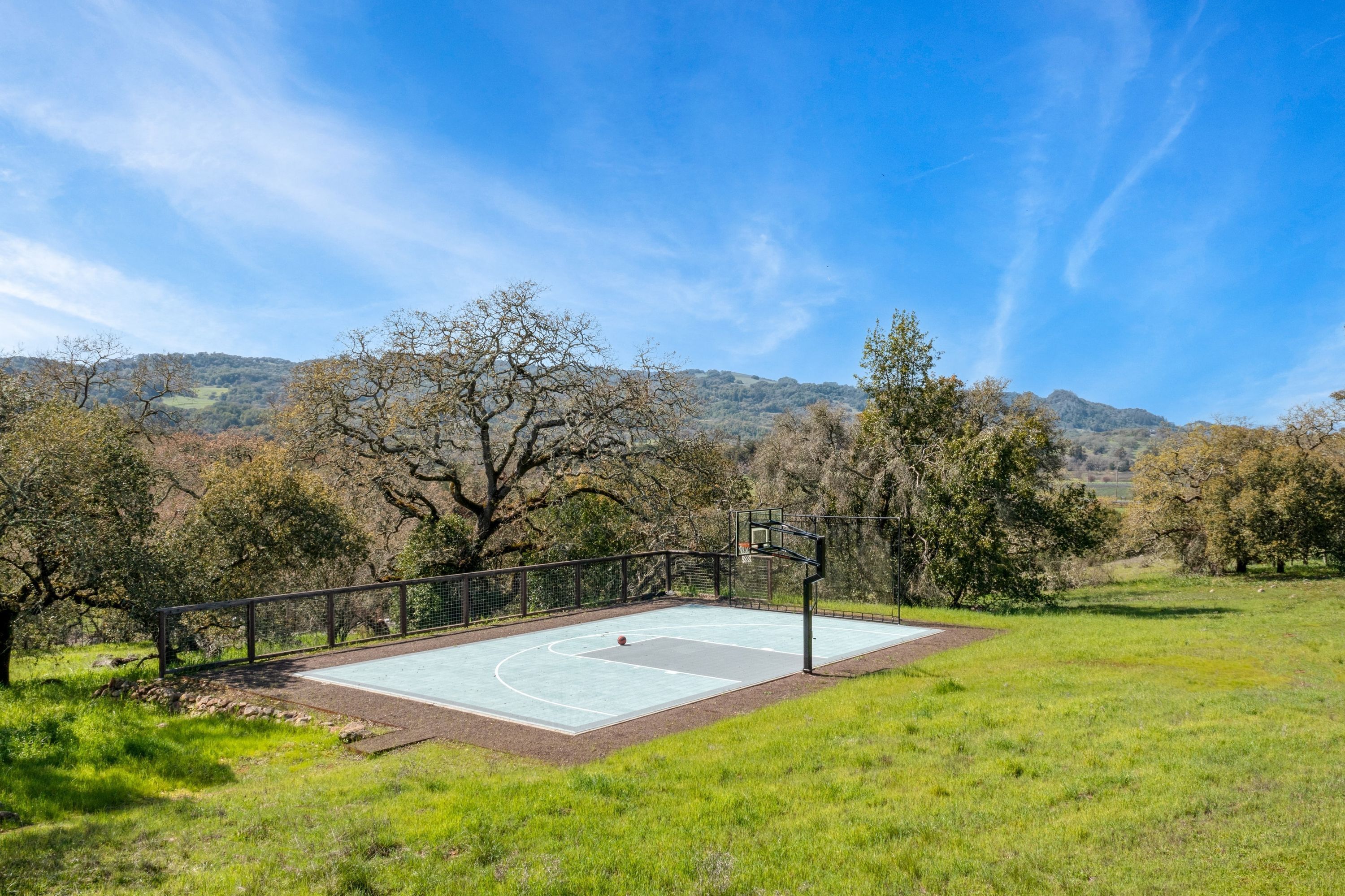 A basketball court surrounded by trees and hills.